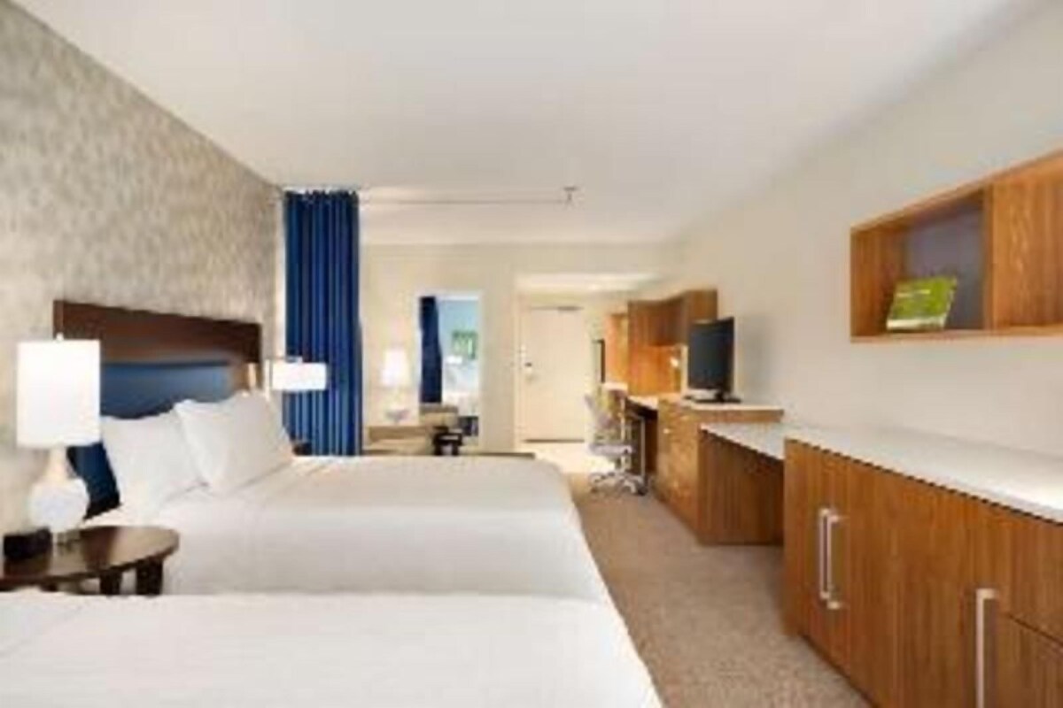 Une chambre d’hôtel avec deux lits, un bureau, une télévision et une armoire.