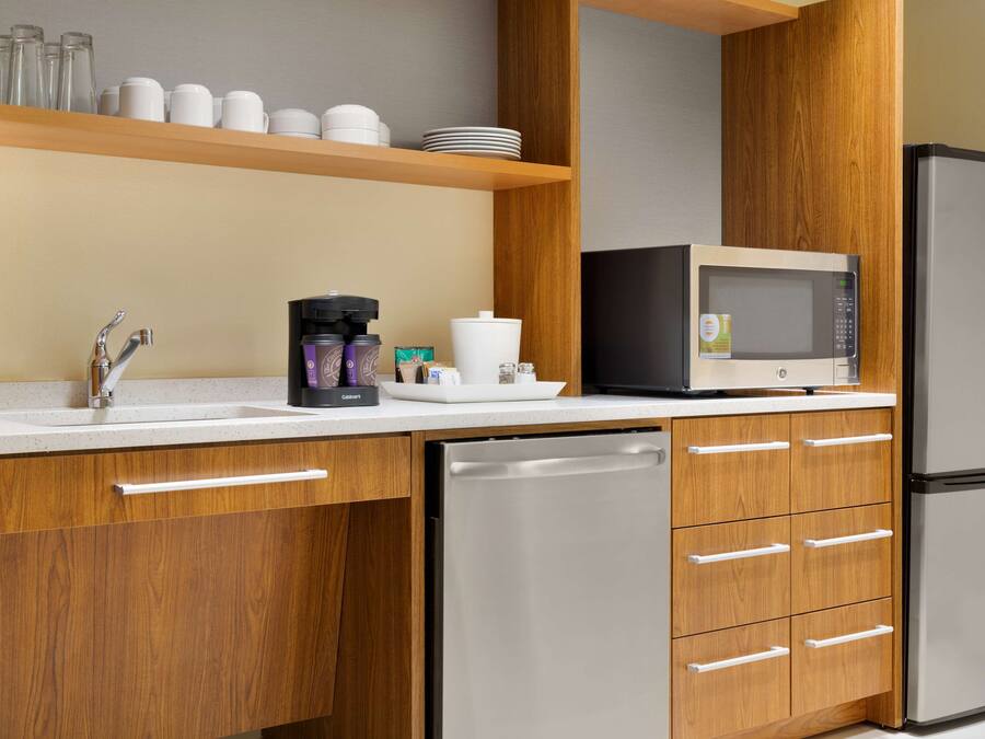 A modern kitchen with wooden cabinets, a stainless steel dishwasher, a microwave, and a coffee maker.