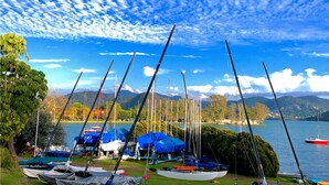 Un puerto deportivo junto al lago con barcos amarrados y cubiertos, rodeado de montañas y árboles.