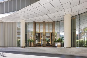 Een modern gebouw met een glazen gevel, brede zuilen en een betegeld plafond.