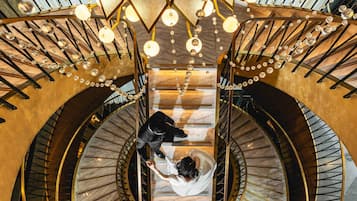 A grand staircase with marble steps and golden railings, leading to an upper floor.
