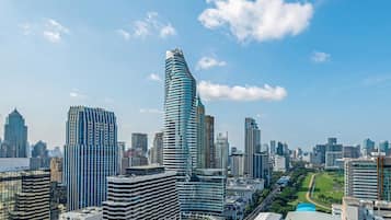 A cityscape with modern high-rise buildings, a prominent curved skyscraper, and a well-maintained park area.