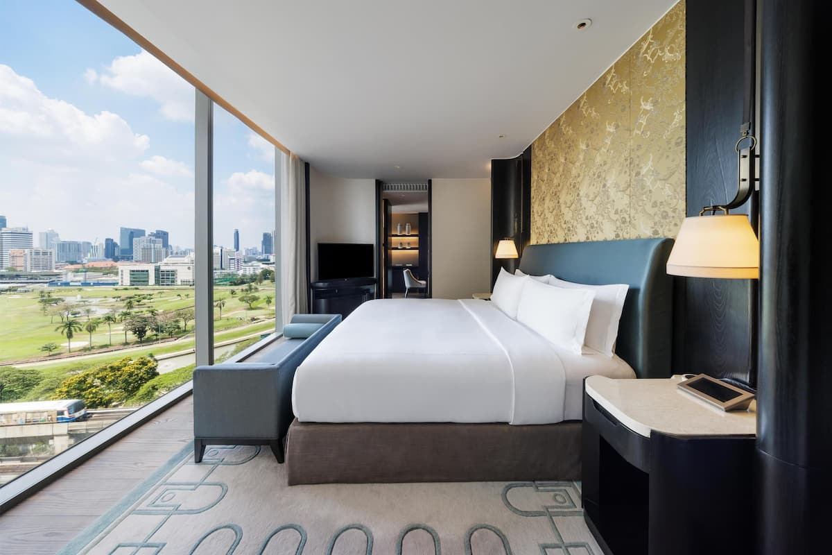 Een hotelkamer met een groot bed, uitzicht op de skyline en een stadspark.