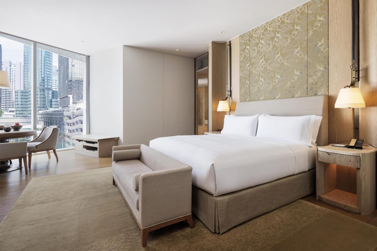 Een moderne hotelkamer met een groot bed, een bureau, een stoel en uitzicht op de stad.