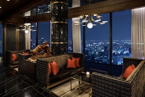 Un interior de rascacielos con vistas a la ciudad, una gran escultura y muebles modernos.