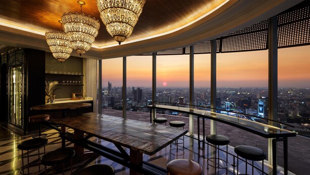 Een bar met uitzicht over de stad, grote kroonluchters en een modern design.