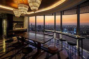 Een bar met uitzicht over de stad, grote kroonluchters en een modern design.