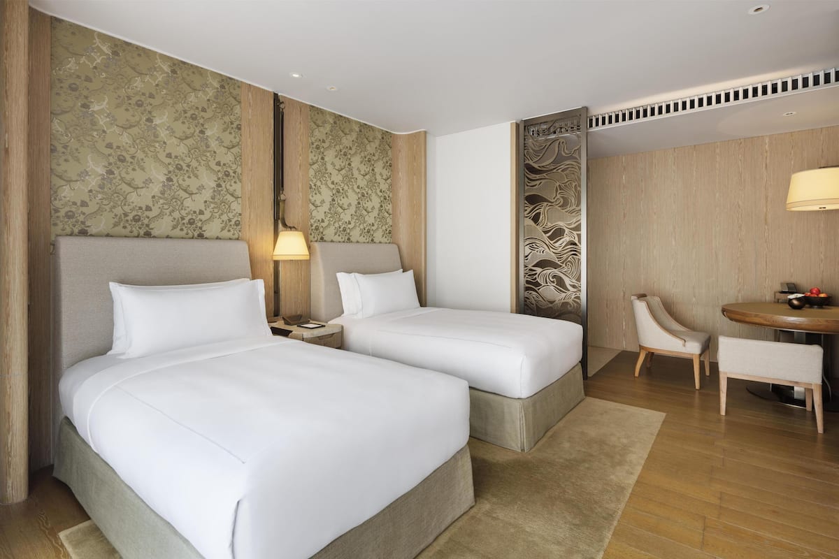 Een hotelkamer met twee bedden, een bureau en een stoel.