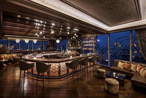 Zona de bar con vista a la ciudad, barra y disposición de asientos.
