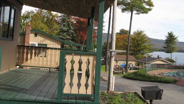 A wooden building with a porch, a swimming pool, and a view of a lake. - Treasure Cove Resort Motel (Diamond Point)