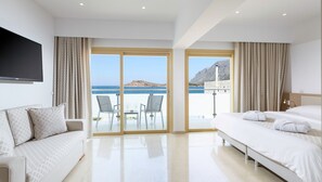 Ein Hotelzimmer mit Balkon, einer Couch, einem Bett und einem Fernseher.
