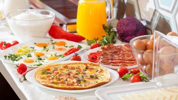 A breakfast spread with eggs, bacon, tomatoes, and a glass of orange juice.