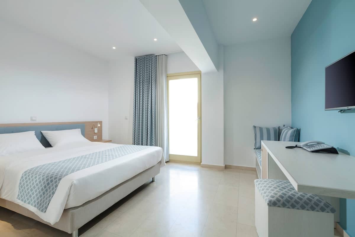 A modern hotel room with a bed, a desk, and a TV.
