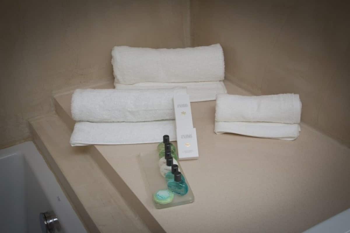A bathroom with a bathtub, two white towels, a bottle of shampoo, and a box of toiletries.