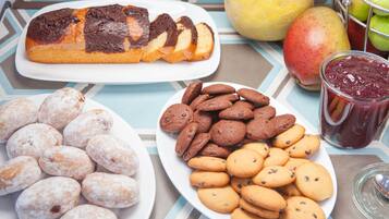Una mesa con pan, platos de galletas, un frasco de mermelada y un melón.