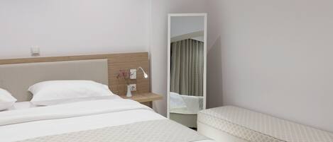 A hotel room with a large bed, a bedside table with a lamp, and a mirror.
