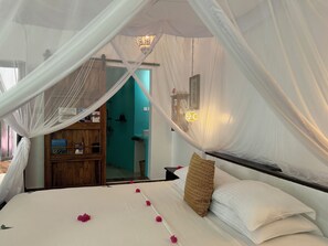 A bedroom with a bed, white curtains, and a wooden cabinet. - Jafferji Beach Retreat (Matemwe)