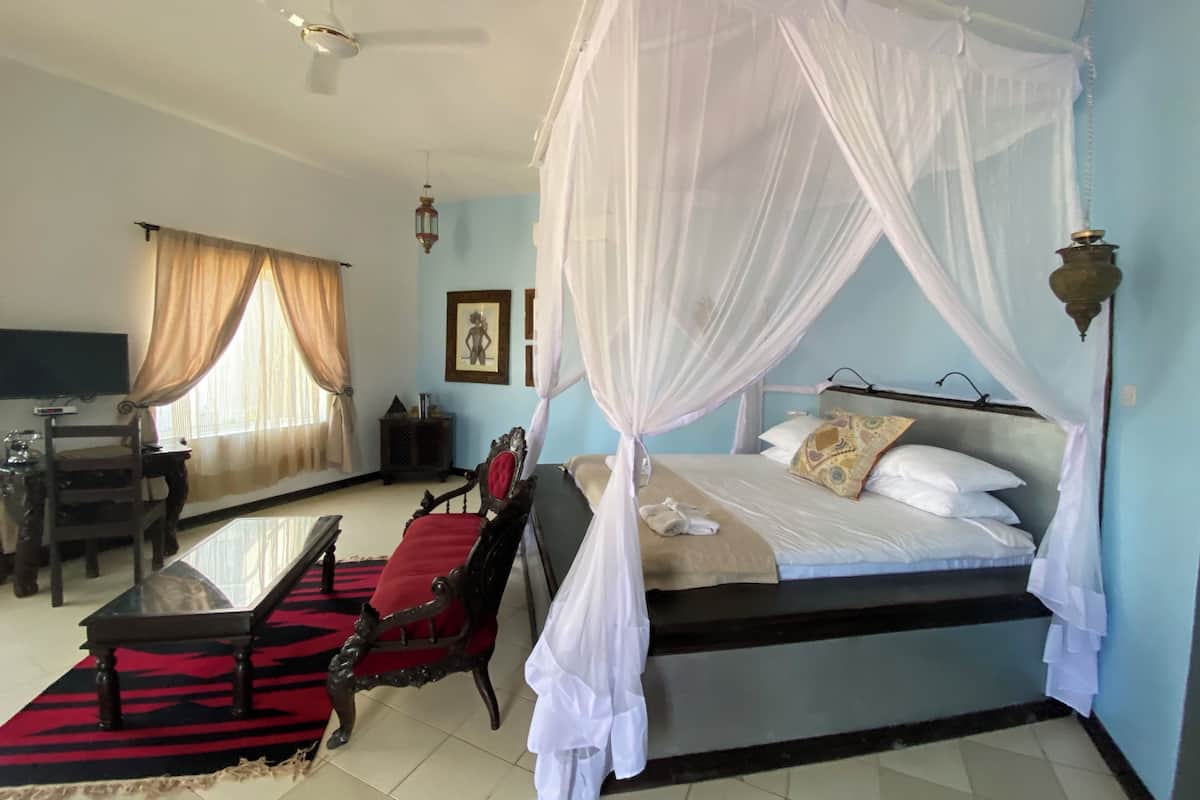A bedroom with a four-poster bed, a desk, and a chair.
