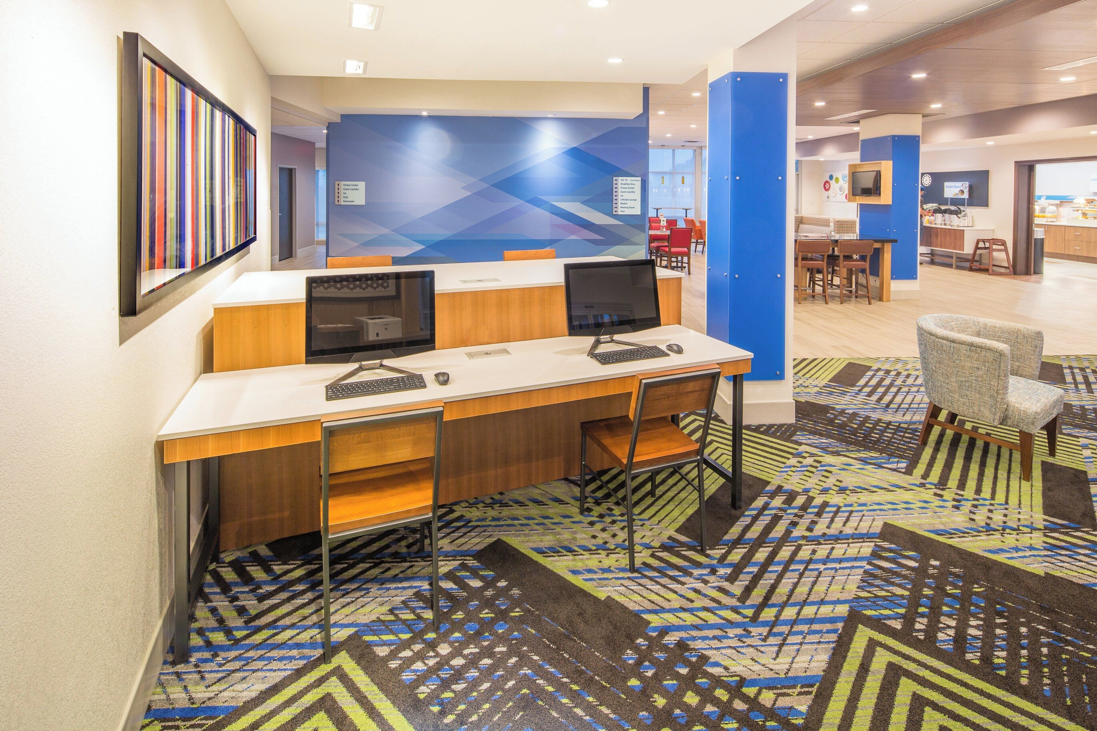 A hotel lobby with a reception desk, computers, and a patterned carpet.