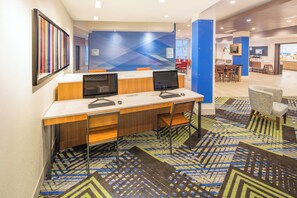 A hotel lobby with a reception desk, computers, and a patterned carpet.