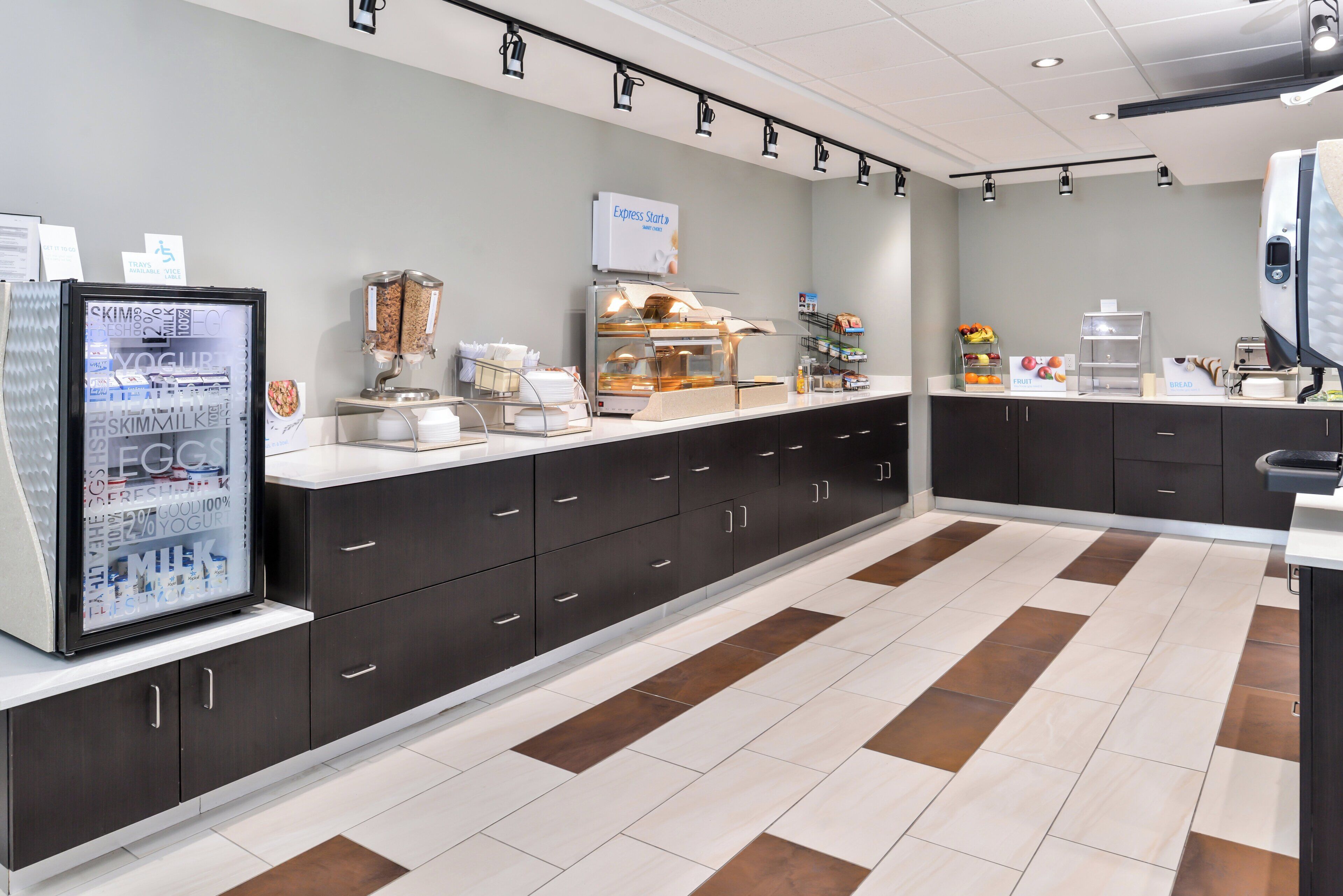 Un área de cocina moderna con refrigerador, dispensadores de alimentos y una cafetera.