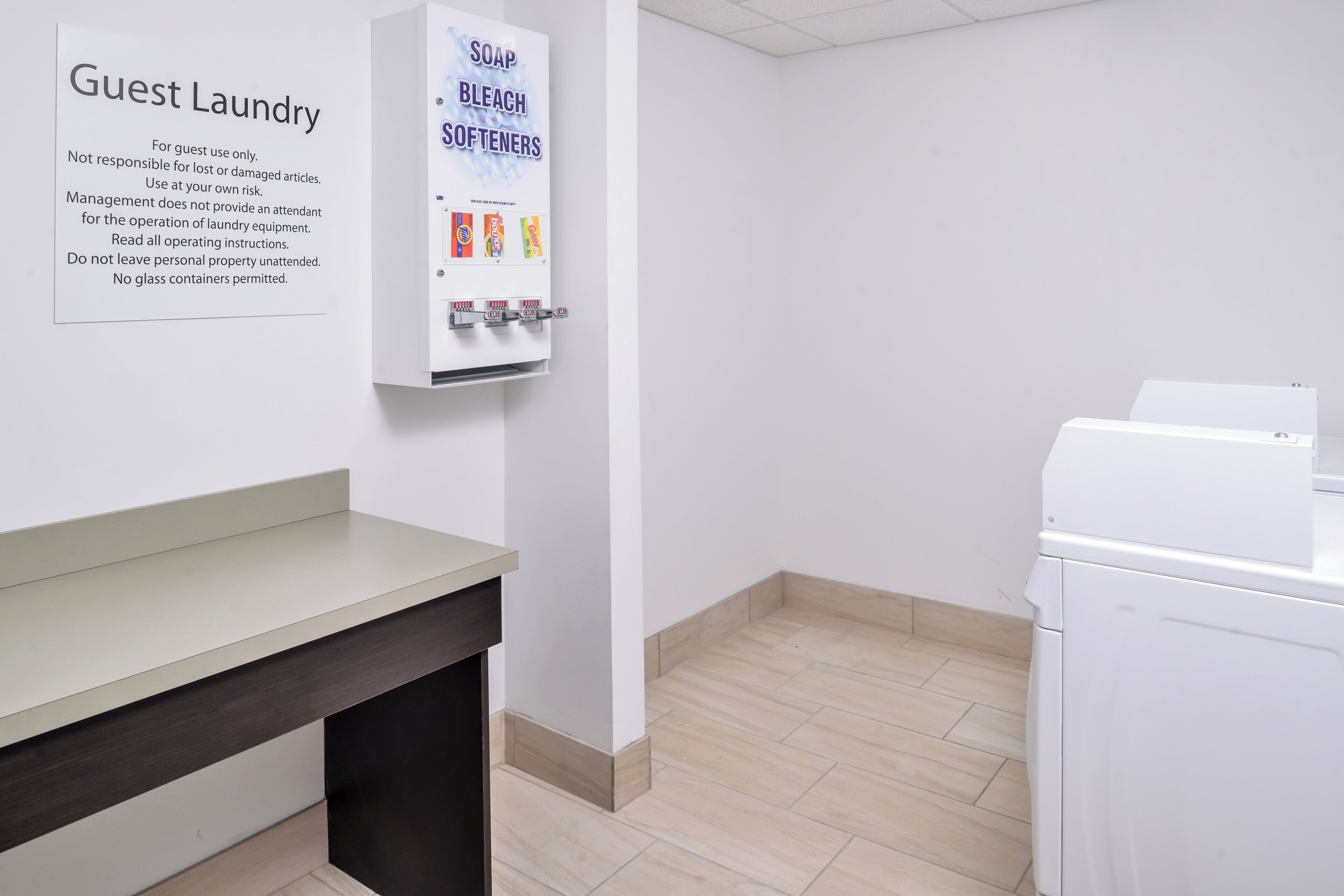 A guest laundry area with a sign detailing usage instructions, a soap and bleach dispenser, and a washing machine.