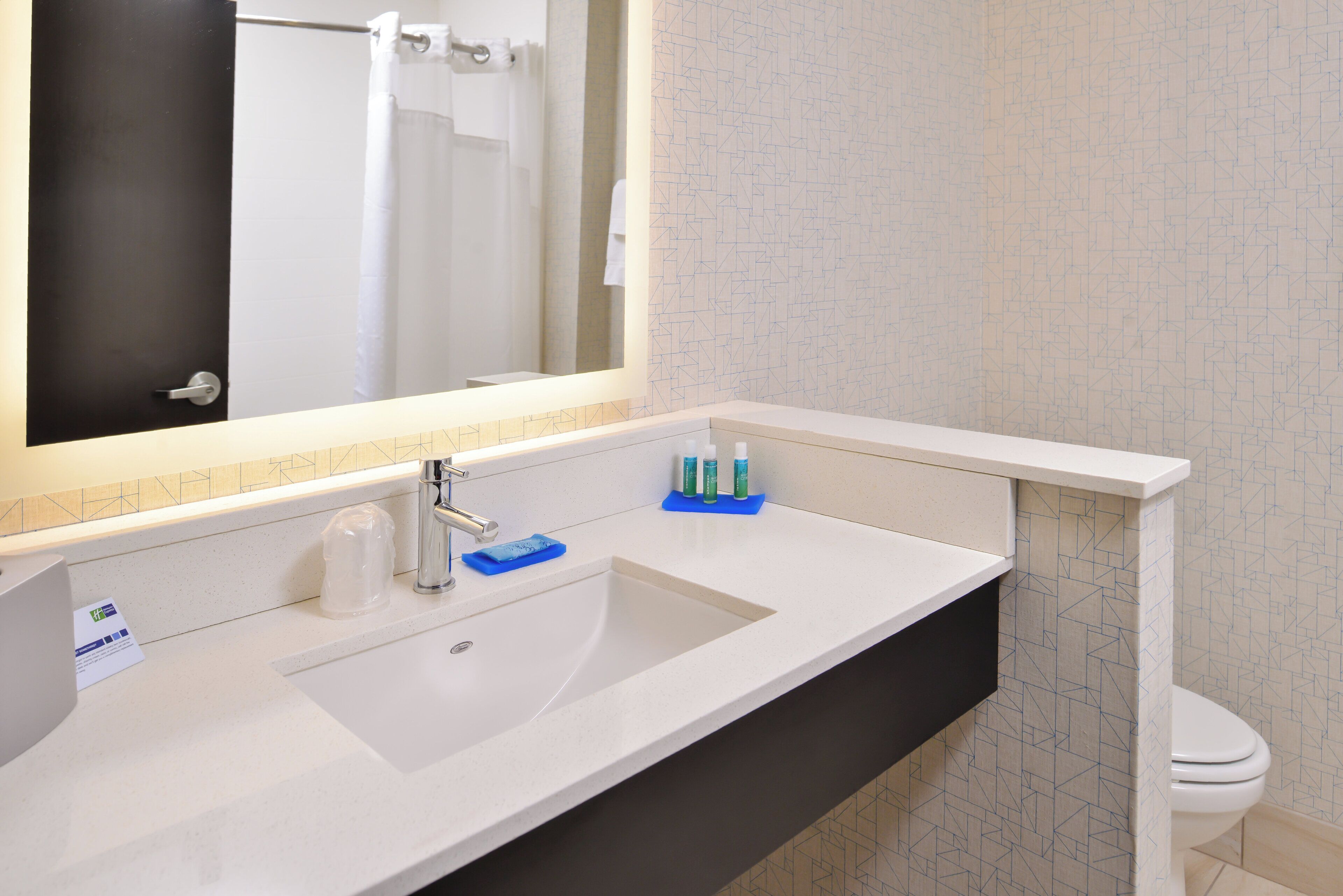 A bathroom with a white sink, a mirror, a towel rack, and a toilet.