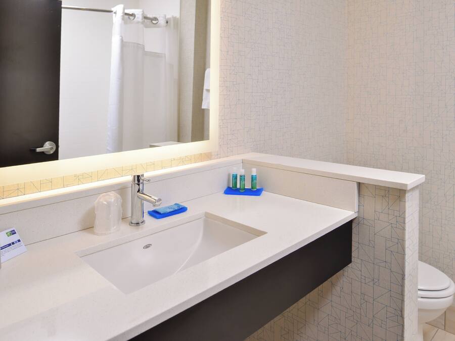 A bathroom with a white sink, a mirror, a towel rack, and a toilet.