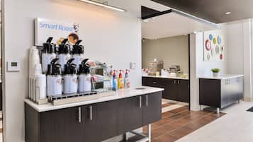Una estación de café moderna con una cafetera digital, cápsulas de café y un dispensador de agua.