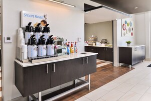 Una estación de café moderna con una cafetera digital, cápsulas de café y un dispensador de agua.