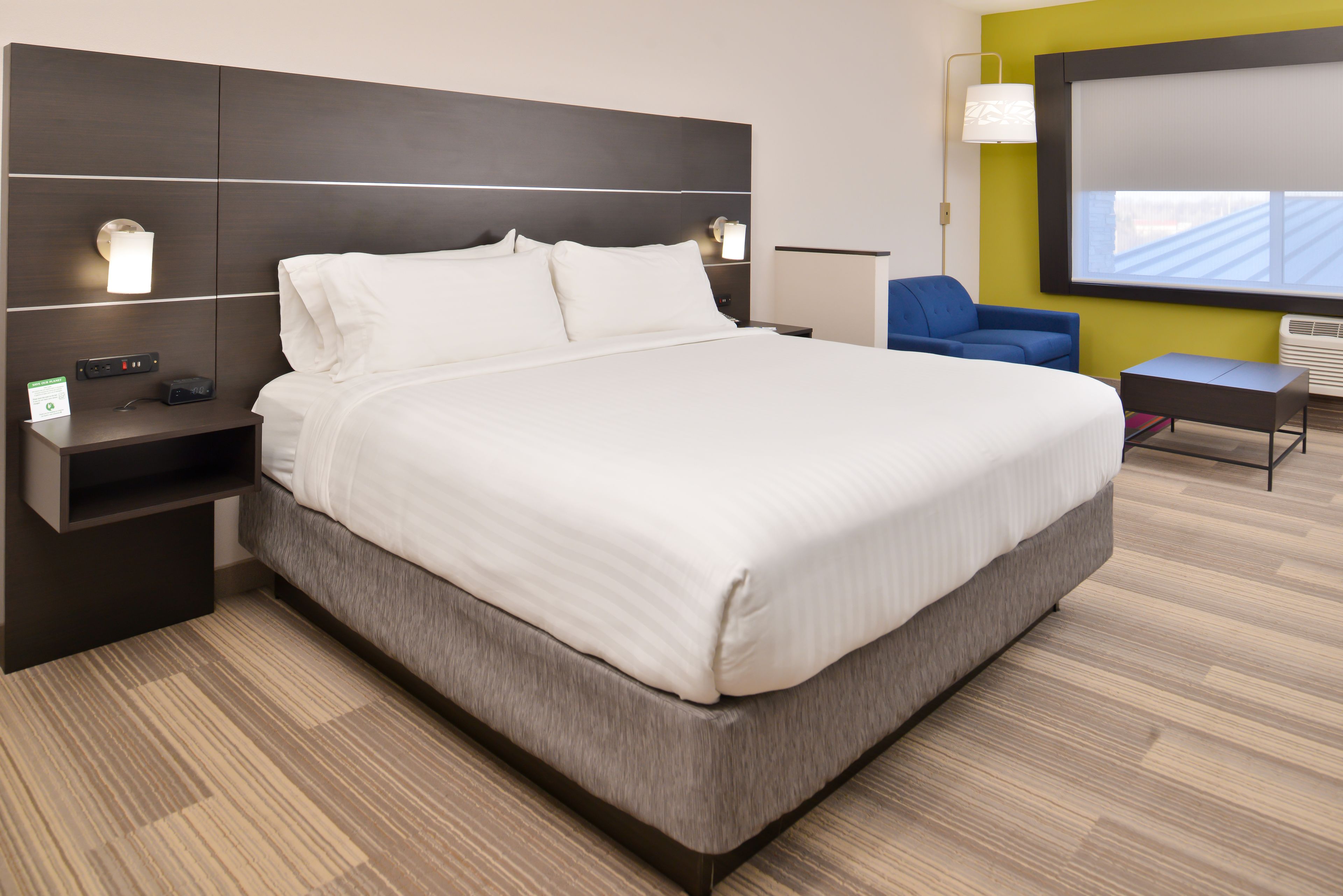 Una habitación de hotel moderna con una cama grande, mesitas de noche, un escritorio y una silla.