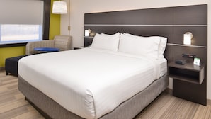 A modern hotel room with a large bed, a small table, a sofa, and a nightstand with a lamp. - Holiday Inn Express & Suites Kansas City - Lee's Summit by IHG (Lee's Summit)