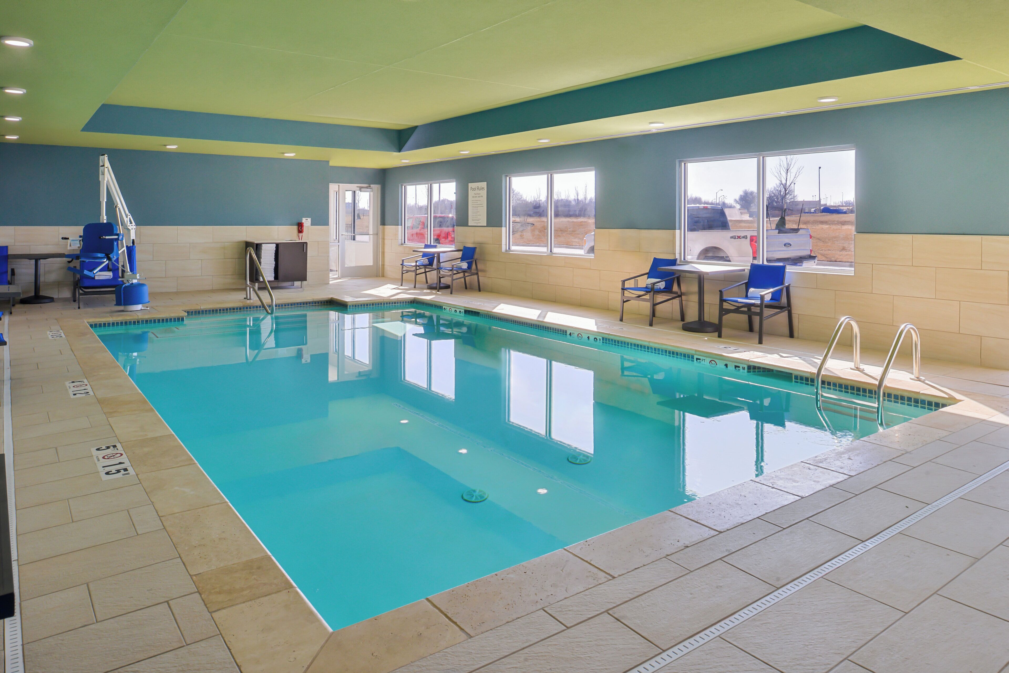 Una piscina interior con agua cristalina, una silla de salvavidas y un ventanal con vistas al exterior.