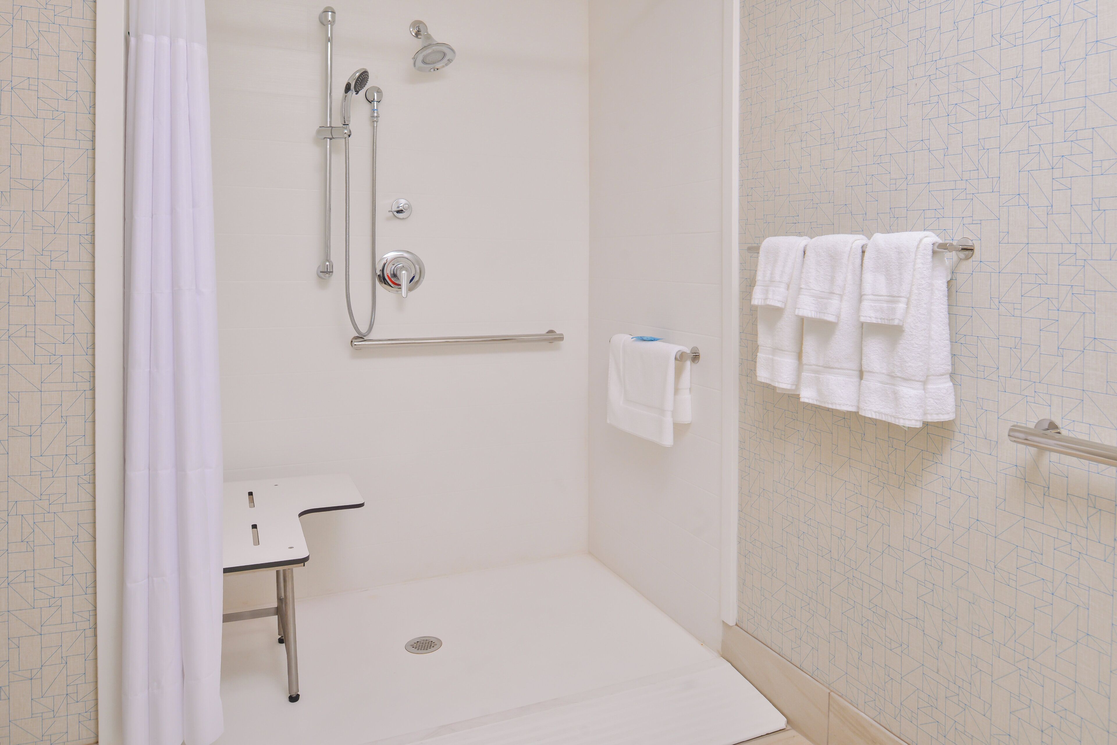A bathroom with a shower, a toilet, and a towel rack.