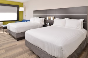 Habitación de hotel con dos camas, un escritorio y un ventanal grande.