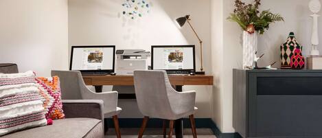 A modern office space with two desks, a couch, and decorative items.