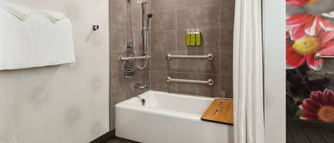 Ein modernes Badezimmer mit einer Badewanne, Dusche und Haltegriffen.