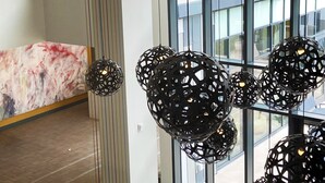A modern interior with a marble reception desk, black spherical pendant lights, and large windows offering a view of the outside. - Hilton Garden Inn Boulder (Boulder)