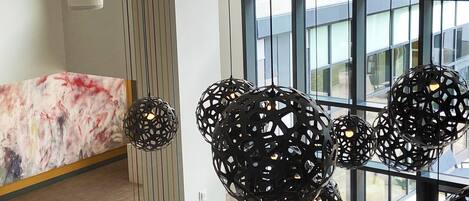 A modern interior with a marble reception desk, black spherical pendant lights, and large windows offering a view of the outside.