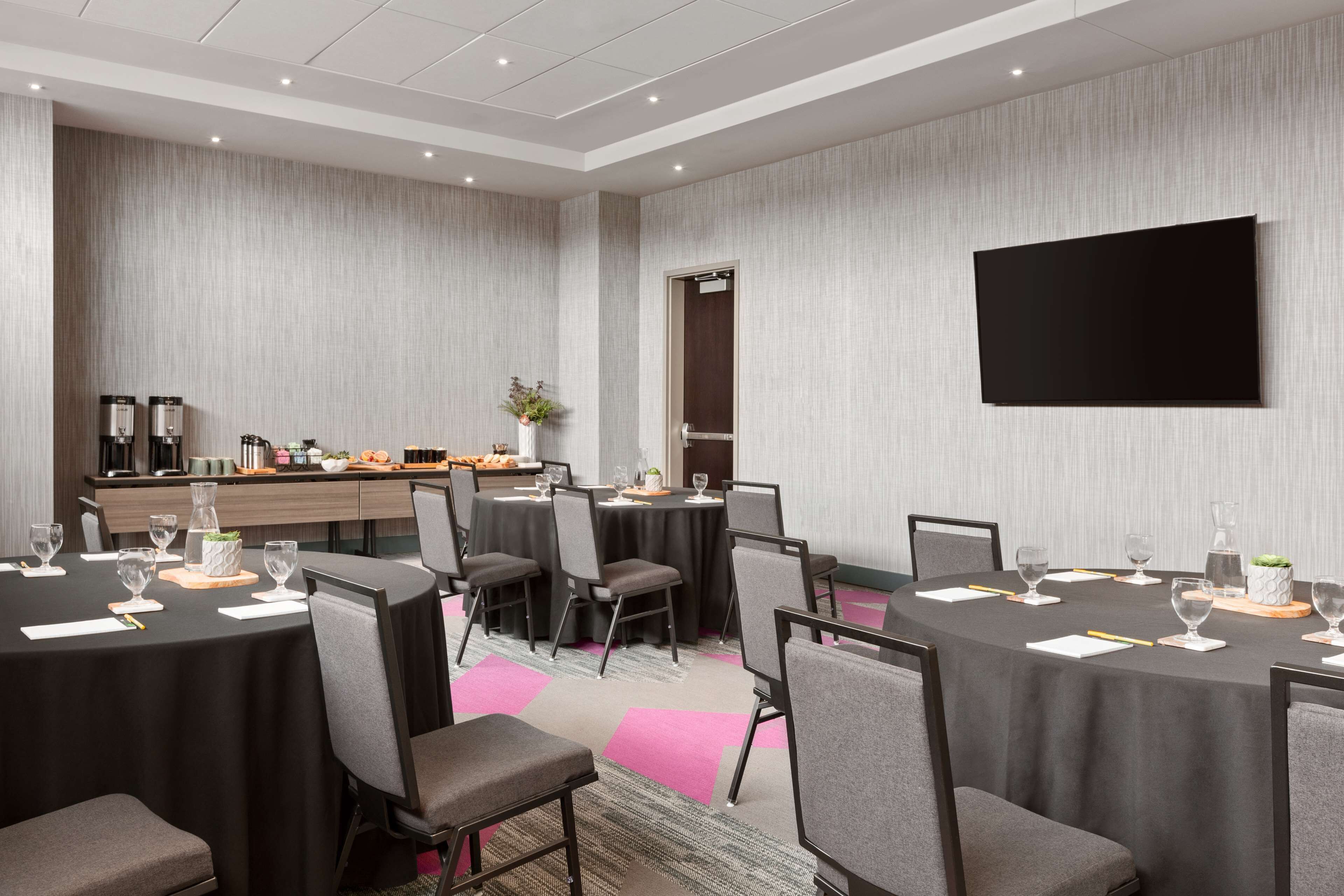 A conference room with round tables, chairs, and a coffee station.