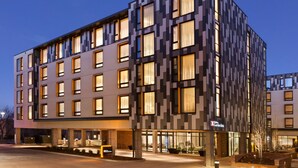 A modern hotel with a geometric facade, multiple balconies, and a well-lit entrance. - Hilton Garden Inn Boulder (Boulder)