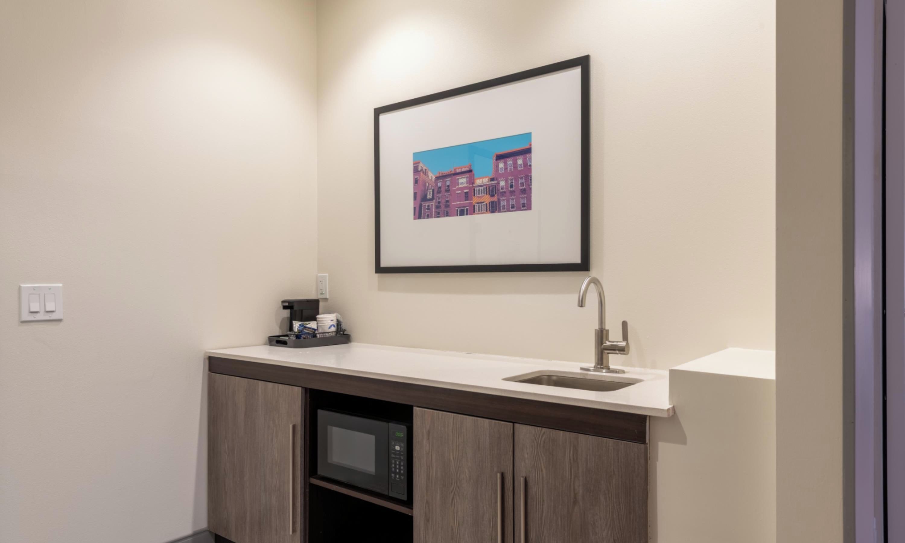 A modern bathroom with a built-in sink, a microwave, and a framed picture on the wall.