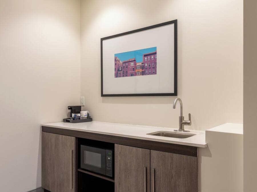 A modern bathroom with a built-in sink, a microwave, and a framed picture on the wall.