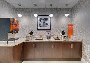 A coffee station with multiple coffee makers and a framed coffee-themed artwork on the wall. - Hampton Inn & Suites Boston/Stoughton (Stoughton)