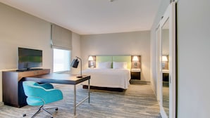 A hotel room with a bed, desk, chair, television, and bedside lamps. - Hampton Inn & Suites Boston/Stoughton (Stoughton)