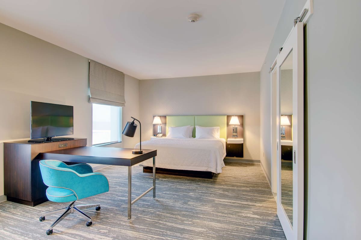 Une chambre d’hôtel équipée d’un lit, d’un bureau, d’une chaise, d’une télévision et de lampes de chevet.