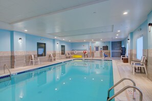 An indoor swimming pool with clear water, surrounded by lounge chairs and a tiled floor. - Hampton Inn & Suites Boston/Stoughton (Stoughton)