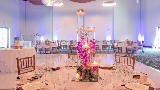 A banquet hall with round tables set for dining, featuring floral centerpieces and candles. - Hampton Inn & Suites Boston/Stoughton (Stoughton)