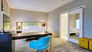 A hotel room with a bed, desk, chair, and a mirror. - Hampton Inn & Suites Boston/Stoughton (Stoughton)