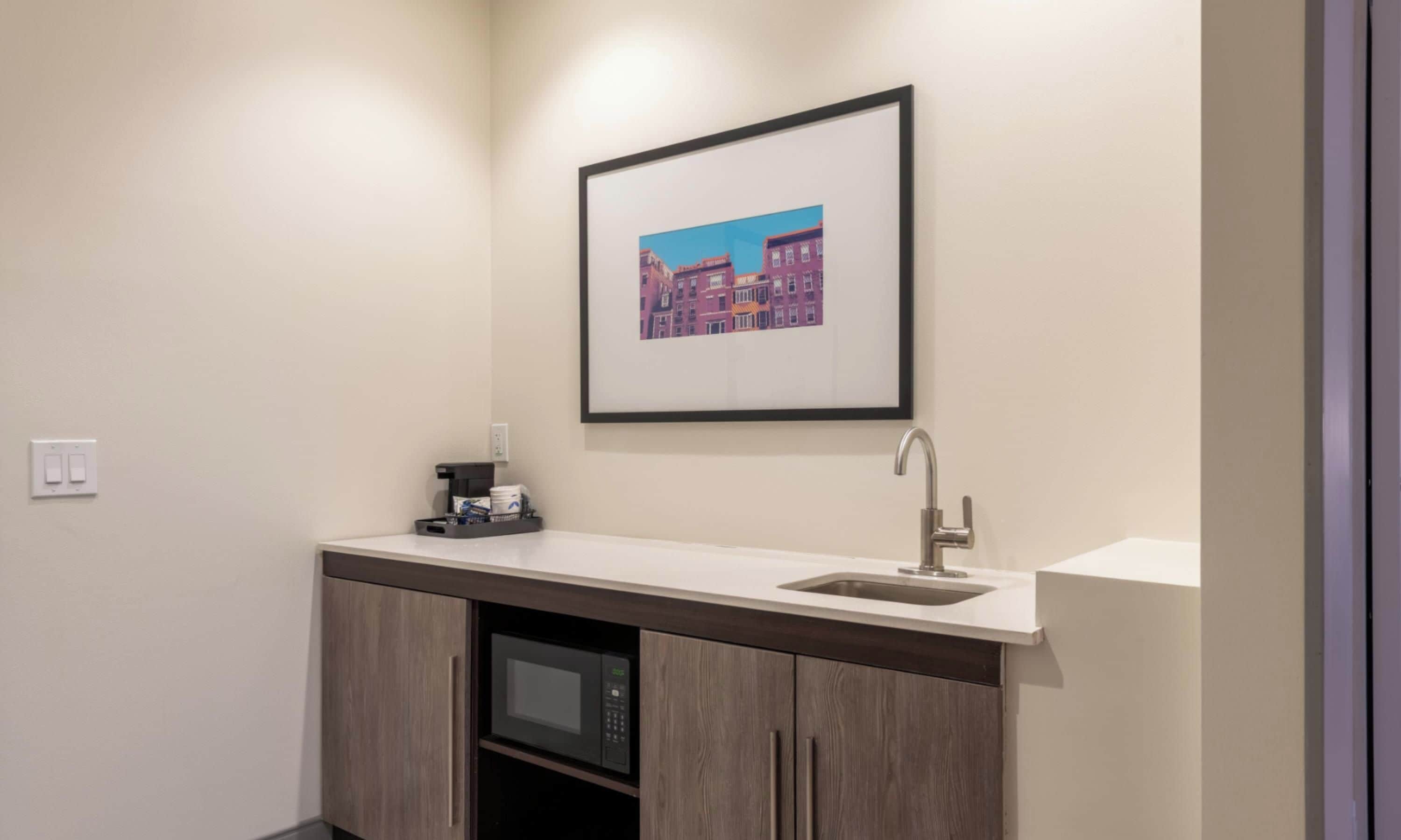 A compact kitchenette with a microwave, a coffee maker, and a sink.